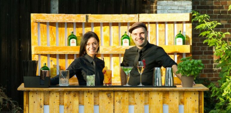 Zwei lächelnde Barkeeper von Flairlab und eine mobile Coktailbar